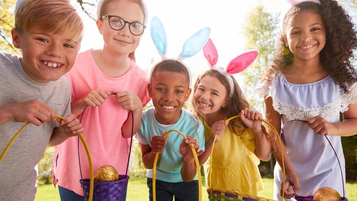 Five children with bunny ears show off their egg baskets