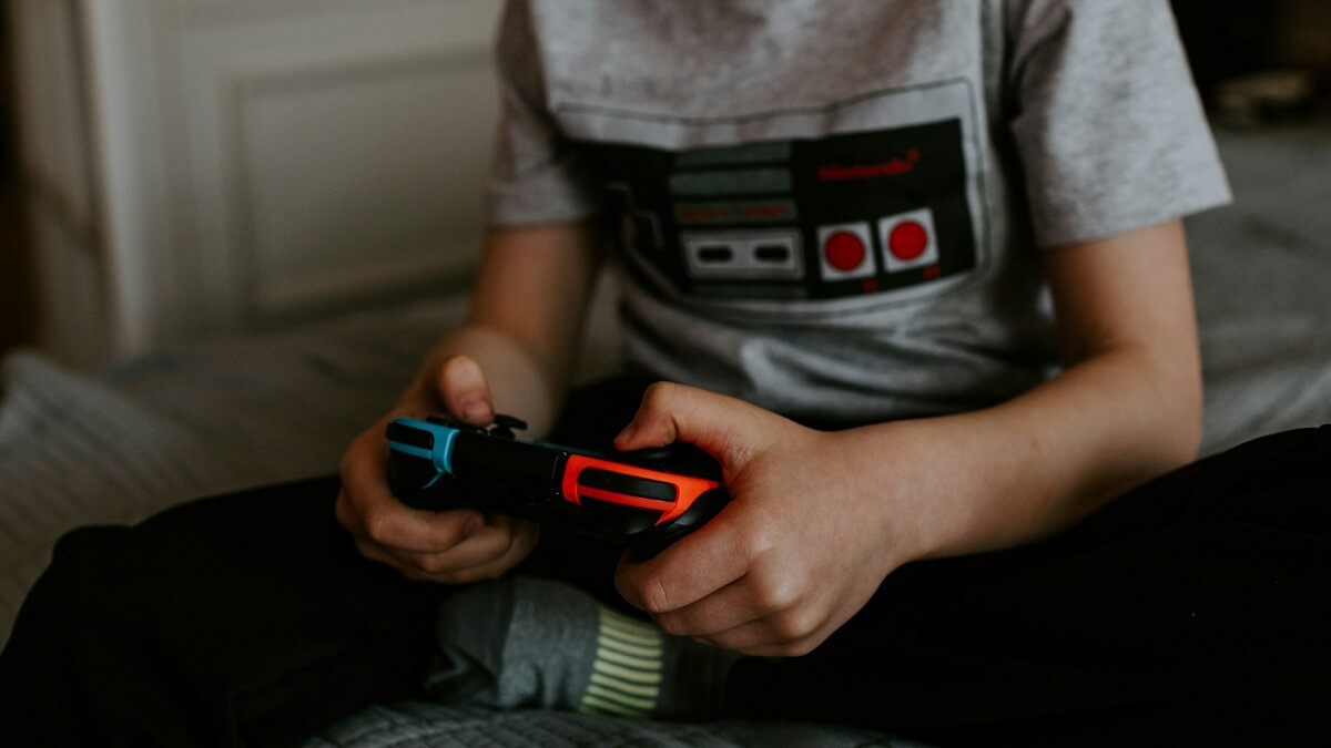A person dressed in a grey t-shirt with hands gripping a game controller